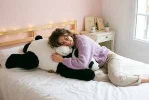 Jeune femme qui serre une peluche panda géante dans sa chambre